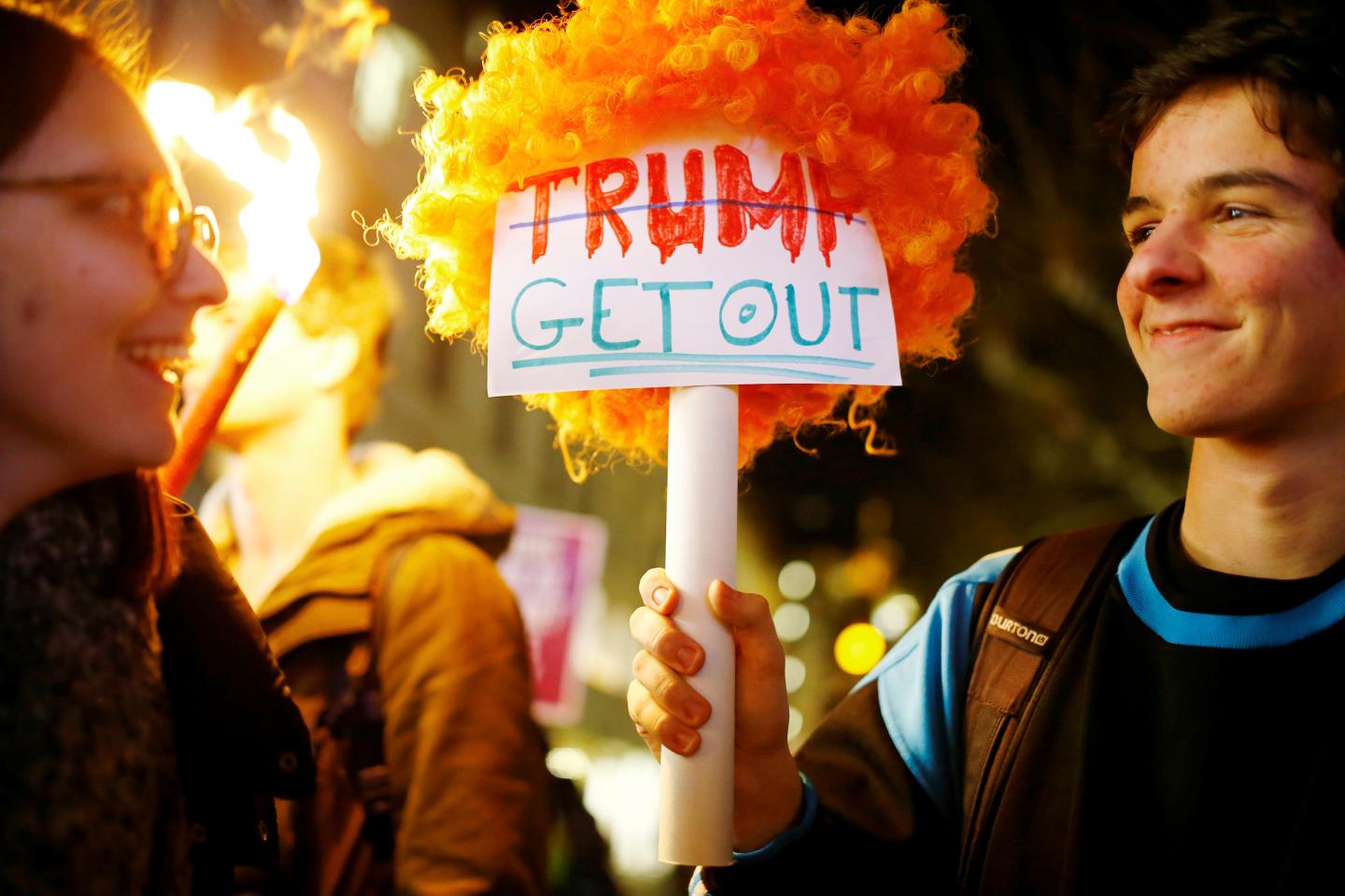 Trump get out, a sign held by young people.